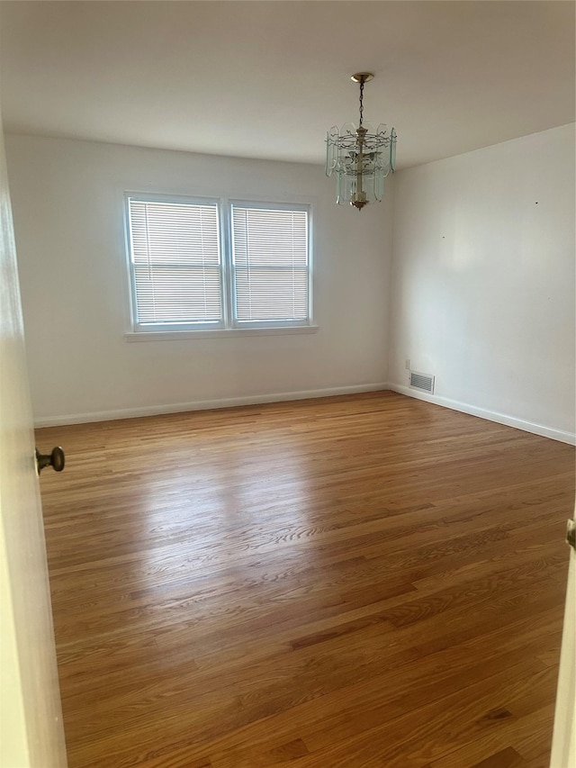 unfurnished room with hardwood / wood-style floors and a chandelier