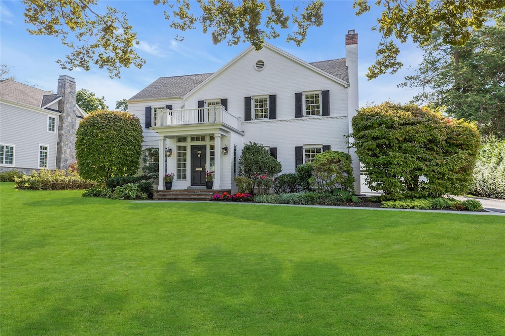 view of front of property with a balcony and a front yard