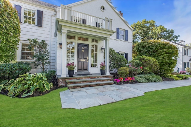 exterior space with a balcony and a front yard