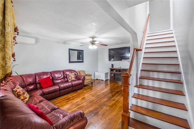 living room featuring a fireplace, wood-type flooring, a wall mounted AC, ceiling fan, and crown molding