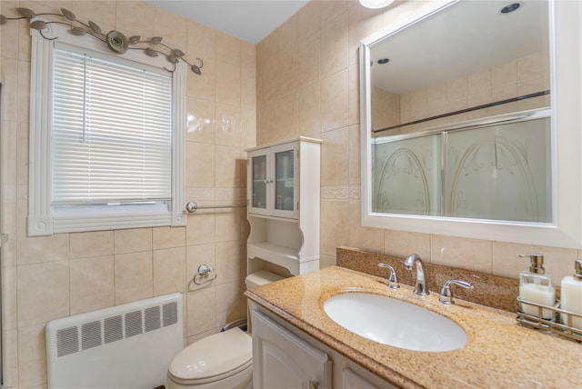 bathroom featuring walk in shower, radiator heating unit, tile walls, and vanity