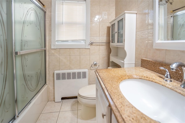 full bathroom with toilet, tile walls, vanity, radiator, and enclosed tub / shower combo