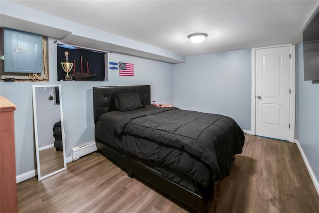 bedroom featuring hardwood / wood-style flooring, electric panel, and baseboard heating