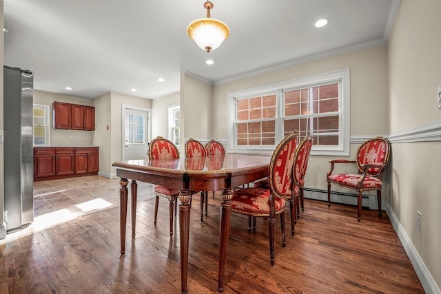 dining room featuring a baseboard heating unit, ornamental molding, and light hardwood / wood-style floors