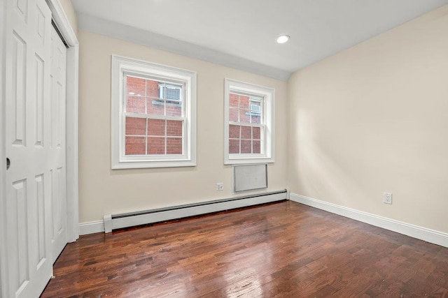 empty room with baseboard heating and dark hardwood / wood-style flooring