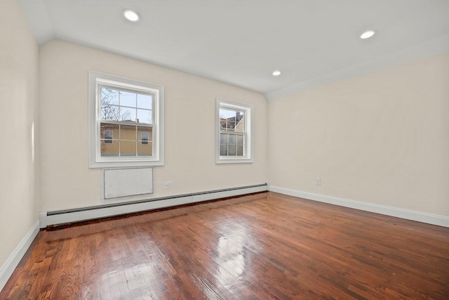 empty room with hardwood / wood-style floors, a baseboard radiator, and vaulted ceiling