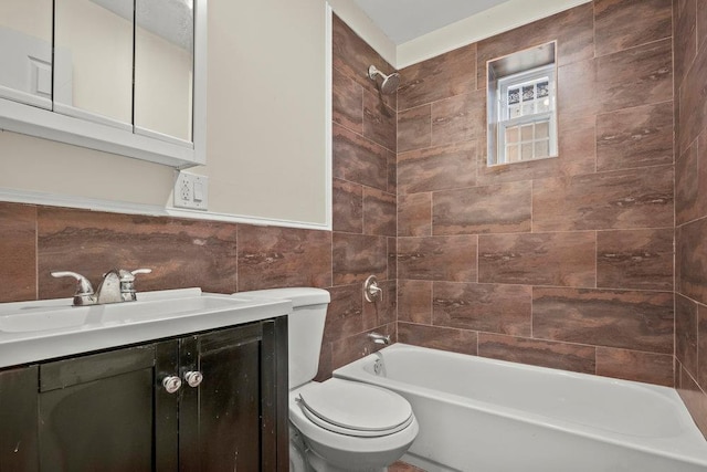 full bathroom with vanity, toilet, tiled shower / bath combo, and tile walls