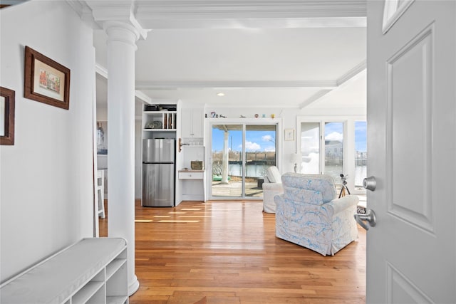 living room featuring decorative columns, crown molding, light wood-type flooring, and beam ceiling