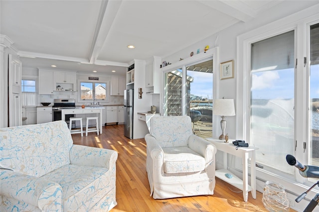 living room with sink, plenty of natural light, and beamed ceiling