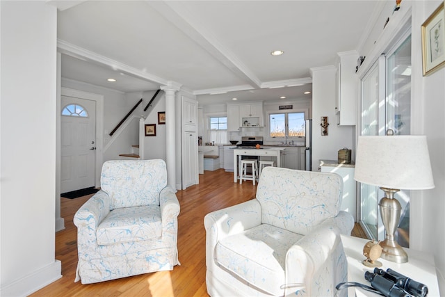 living room featuring crown molding, beam ceiling, and light hardwood / wood-style flooring