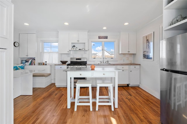 kitchen featuring a kitchen bar, sink, white cabinetry, ornamental molding, and appliances with stainless steel finishes