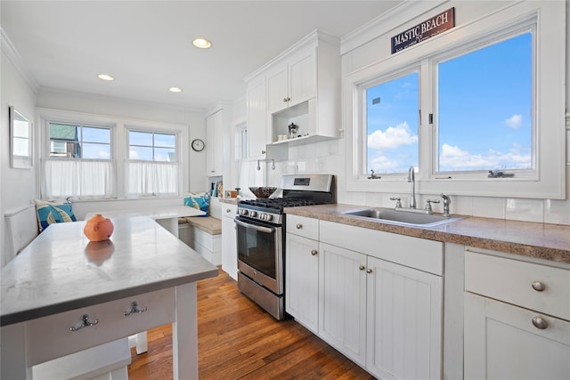 kitchen featuring sink, dark wood-type flooring, white cabinetry, ornamental molding, and stainless steel range with gas cooktop