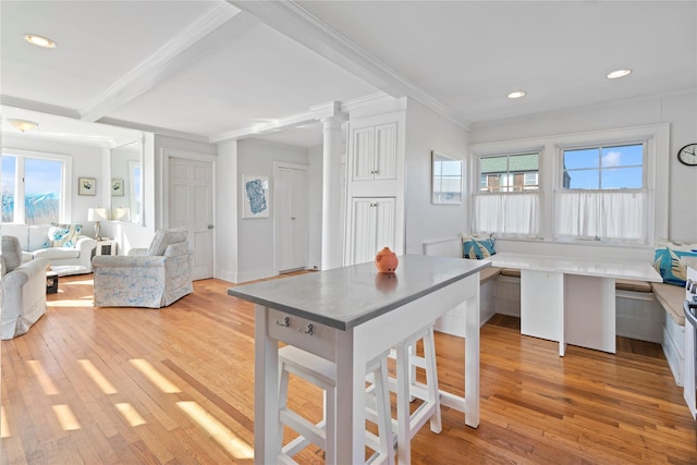 kitchen with a breakfast bar, white cabinetry, light hardwood / wood-style floors, breakfast area, and crown molding