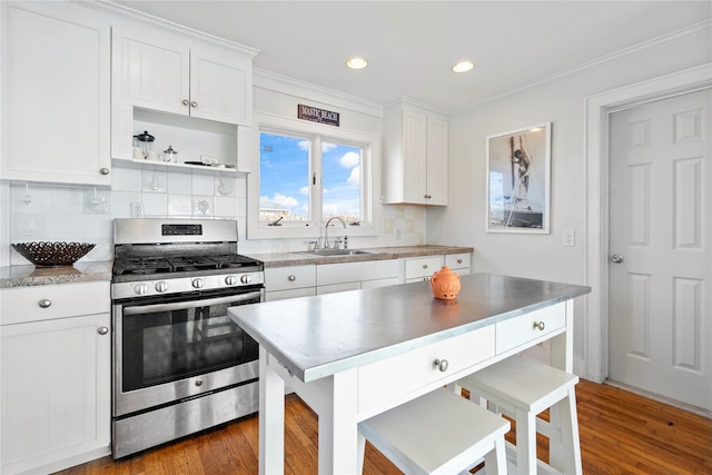 kitchen with sink, a breakfast bar area, white cabinetry, stainless steel range with gas stovetop, and wood-type flooring