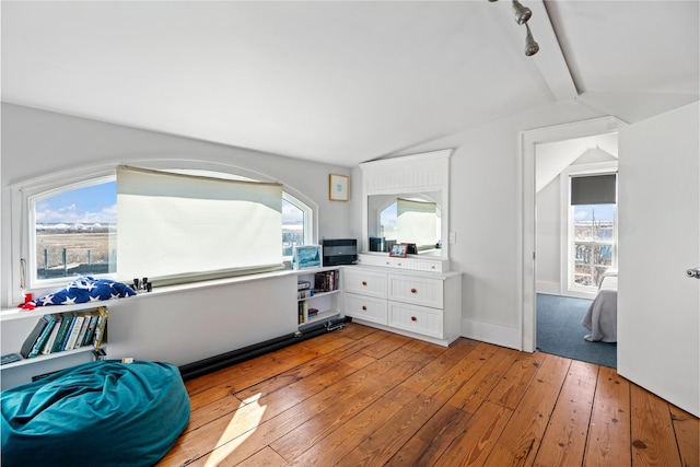 interior space with lofted ceiling with beams and light hardwood / wood-style flooring