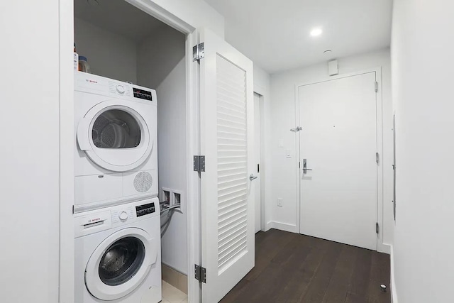 washroom with dark hardwood / wood-style floors and stacked washing maching and dryer