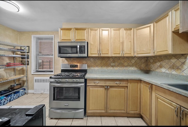 kitchen featuring light brown cabinetry, light tile patterned floors, radiator heating unit, and stainless steel appliances