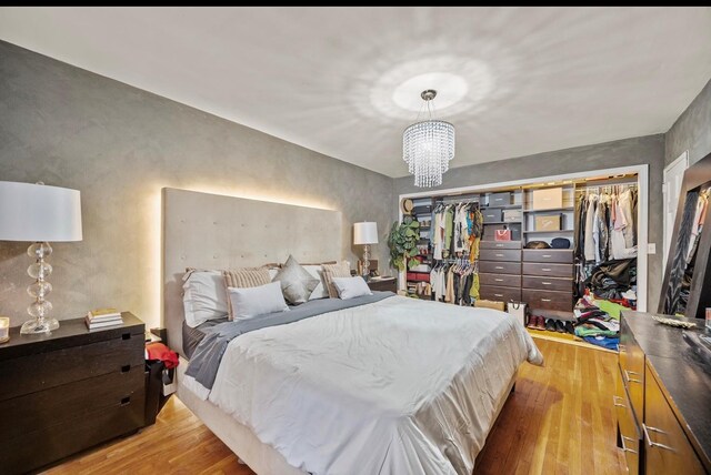 bedroom with a notable chandelier, light wood-type flooring, and a closet