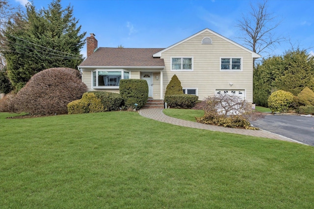 split level home featuring a garage and a front lawn