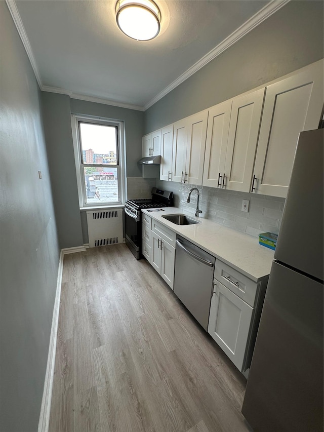 kitchen featuring white cabinetry, appliances with stainless steel finishes, sink, and radiator heating unit