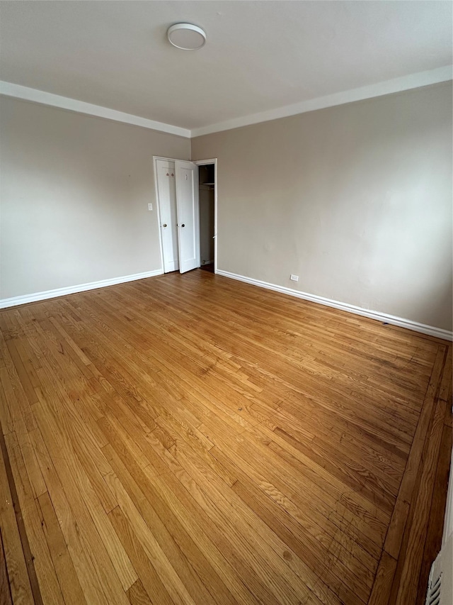 empty room with crown molding and light hardwood / wood-style flooring