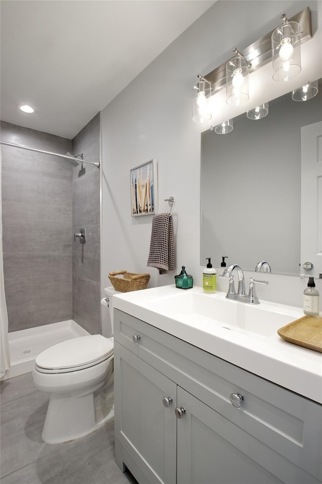 bathroom with vanity, a tile shower, and toilet