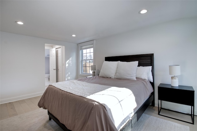 bedroom with ensuite bathroom and light hardwood / wood-style floors