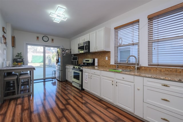 kitchen featuring light stone counters, sink, white cabinets, and appliances with stainless steel finishes