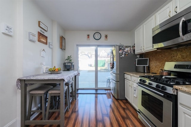 kitchen featuring white cabinetry, light stone counters, dark hardwood / wood-style floors, and appliances with stainless steel finishes