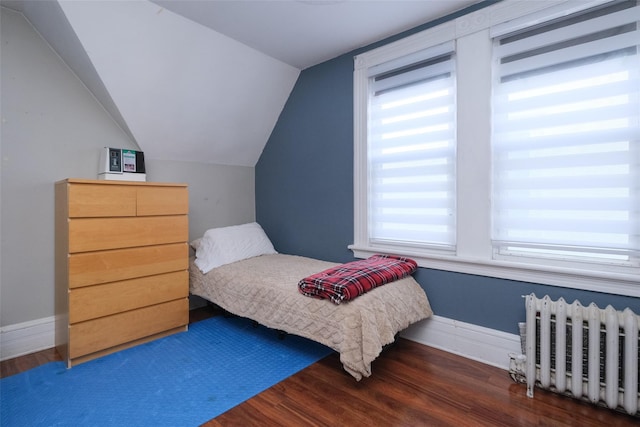 bedroom with dark wood-type flooring, radiator heating unit, and vaulted ceiling