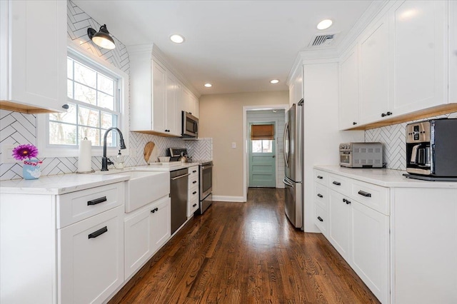 kitchen featuring appliances with stainless steel finishes, dark hardwood / wood-style floors, tasteful backsplash, sink, and white cabinets