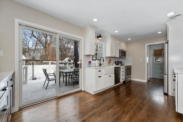 kitchen featuring dark hardwood / wood-style flooring, stainless steel appliances, light stone countertops, decorative backsplash, and white cabinets