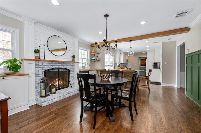 dining area with beamed ceiling, crown molding, a brick fireplace, and dark hardwood / wood-style floors