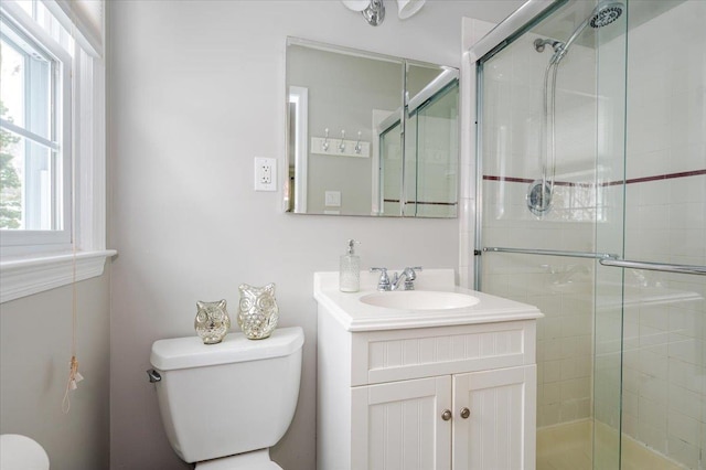 bathroom featuring a shower with door, vanity, and toilet