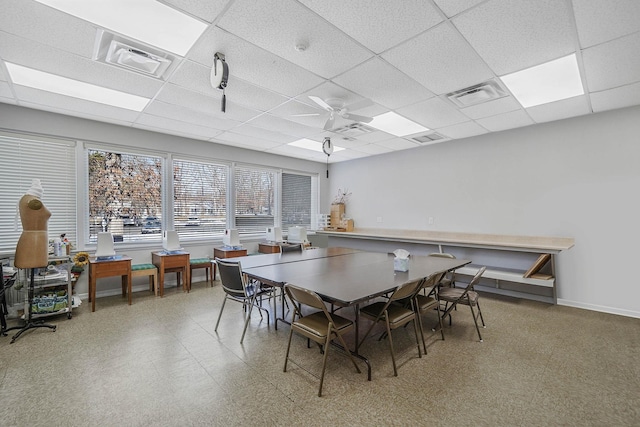 dining area featuring ceiling fan and a drop ceiling