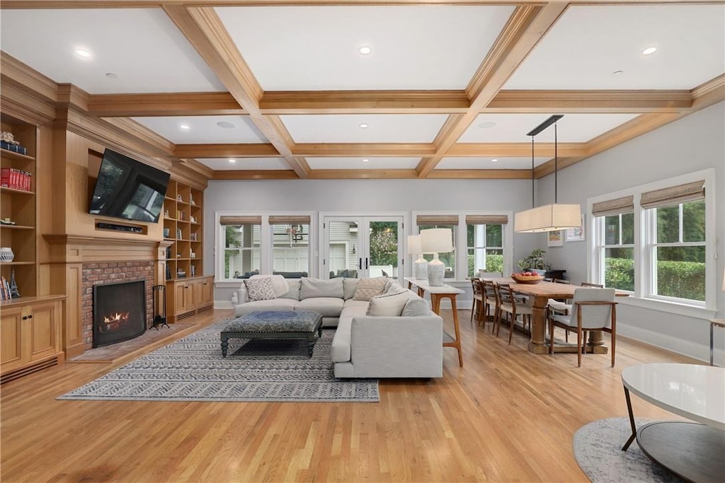 living room featuring a fireplace, beamed ceiling, light hardwood / wood-style flooring, coffered ceiling, and built in shelves