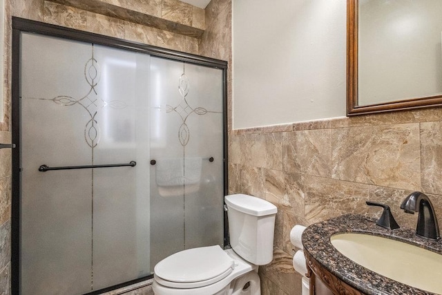 bathroom with tile walls, vanity, toilet, and walk in shower