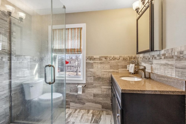 bathroom featuring vanity, toilet, an enclosed shower, and tile walls