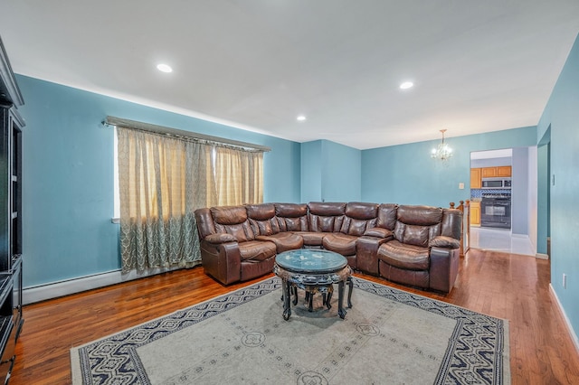 living room with hardwood / wood-style flooring, a baseboard radiator, and a chandelier