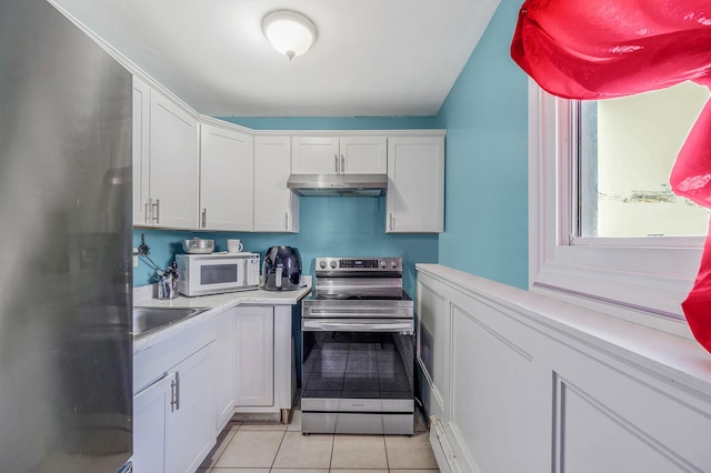 kitchen featuring stainless steel appliances, sink, light tile patterned floors, and white cabinets