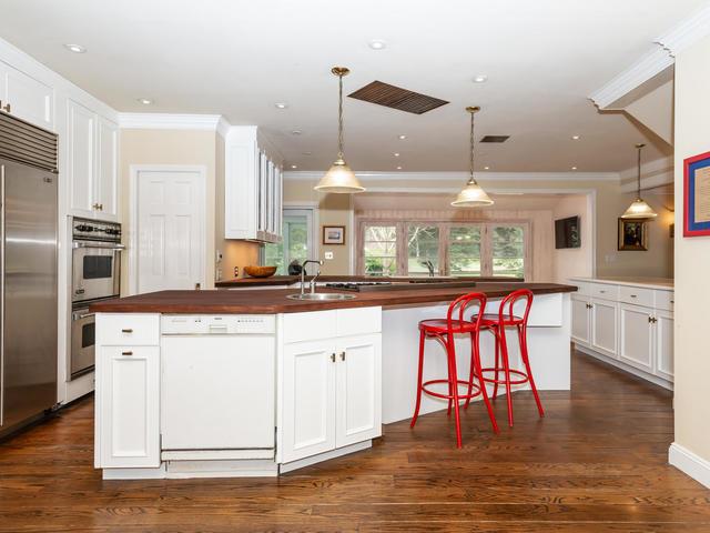 kitchen featuring decorative light fixtures, white cabinets, stainless steel appliances, a healthy amount of sunlight, and a center island with sink