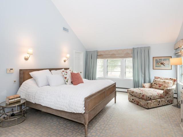 bedroom with a baseboard heating unit, light carpet, and high vaulted ceiling