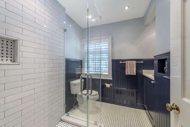 bathroom with radiator heating unit, a shower with shower door, vanity, toilet, and tile patterned floors