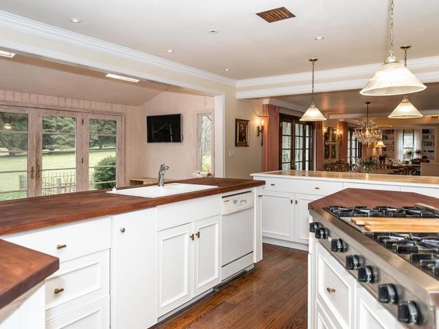 kitchen with white dishwasher, sink, pendant lighting, and butcher block counters