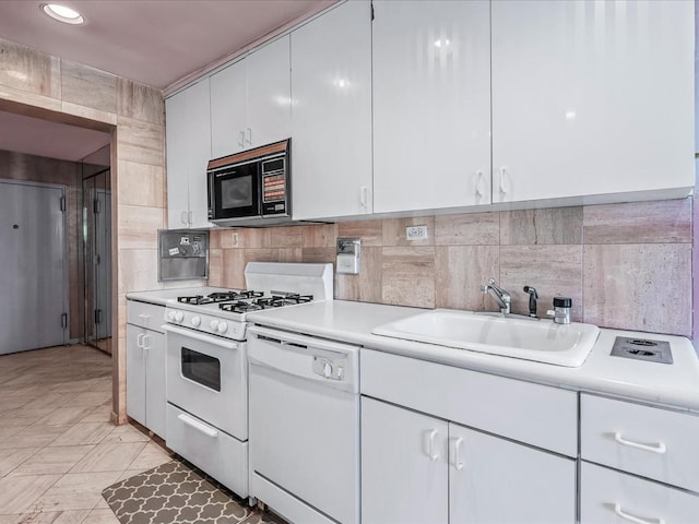 kitchen with sink, white appliances, white cabinets, and backsplash