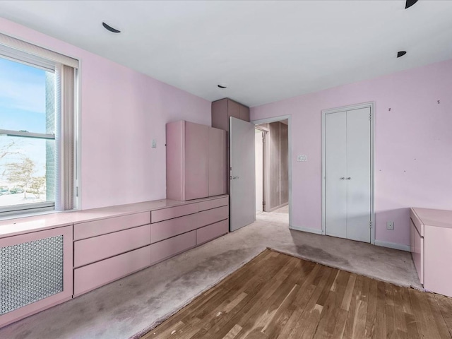 unfurnished bedroom featuring radiator heating unit, a closet, and light wood-type flooring