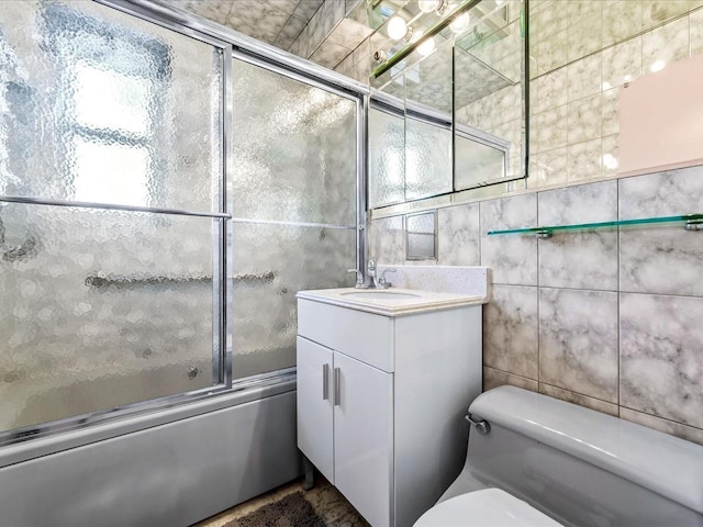 full bathroom with tile walls, vanity, toilet, and combined bath / shower with glass door