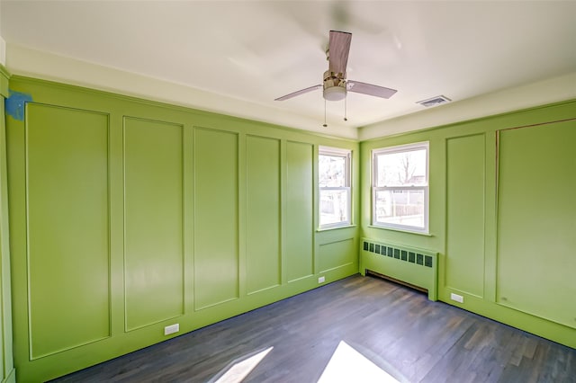 unfurnished bedroom featuring dark hardwood / wood-style floors, radiator heating unit, and ceiling fan