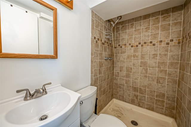 bathroom with vanity, toilet, and a tile shower