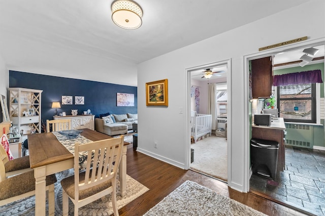 dining room featuring dark wood-style flooring, baseboards, and radiator heating unit